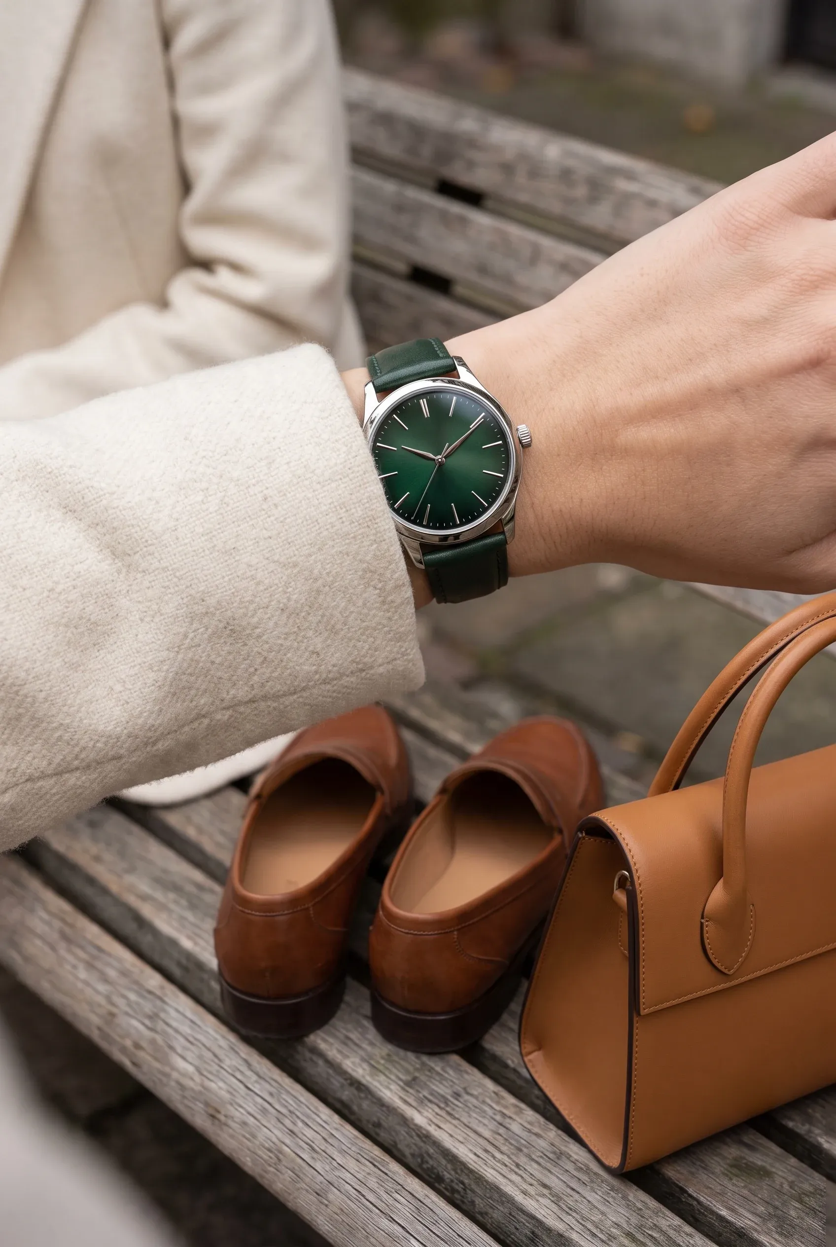 Dark green dial watch styled with a cream blazer and tan accessories for everyday wear.