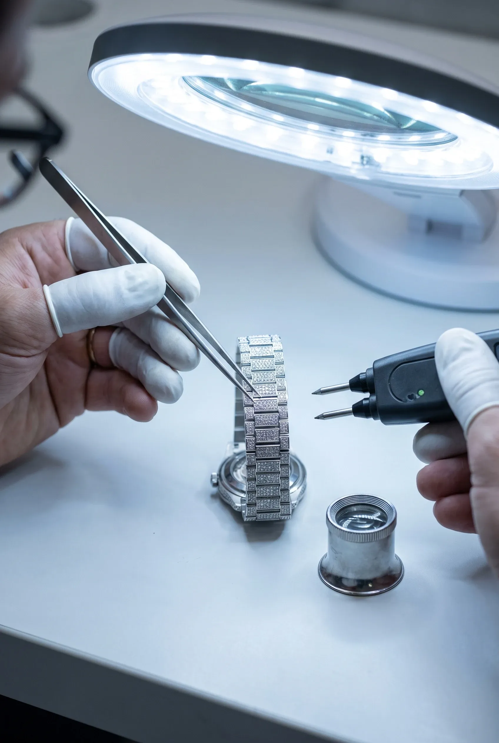 Jeweler inspecting stone security and testing an iced bracelet watch at the final quality stage.