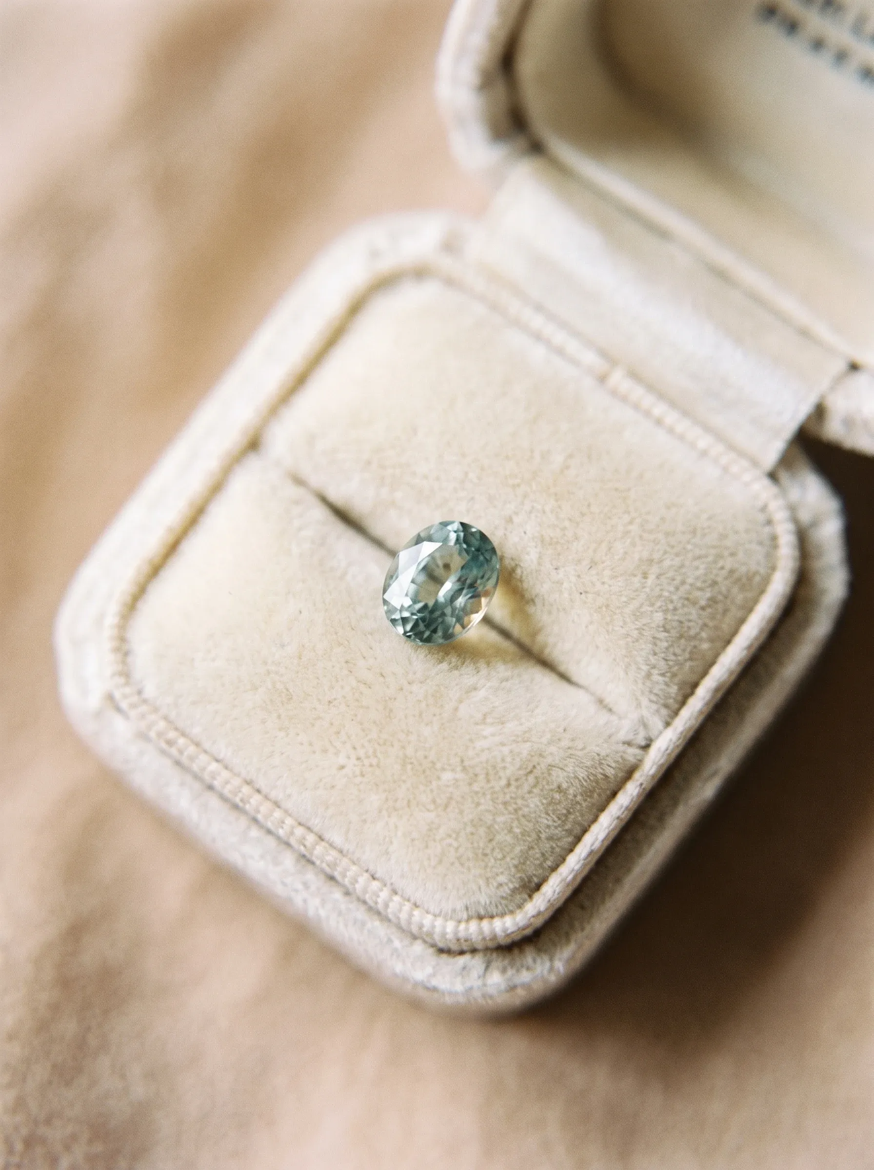 Loose oval stone presented in a cream velvet ring box, photographed in soft natural light