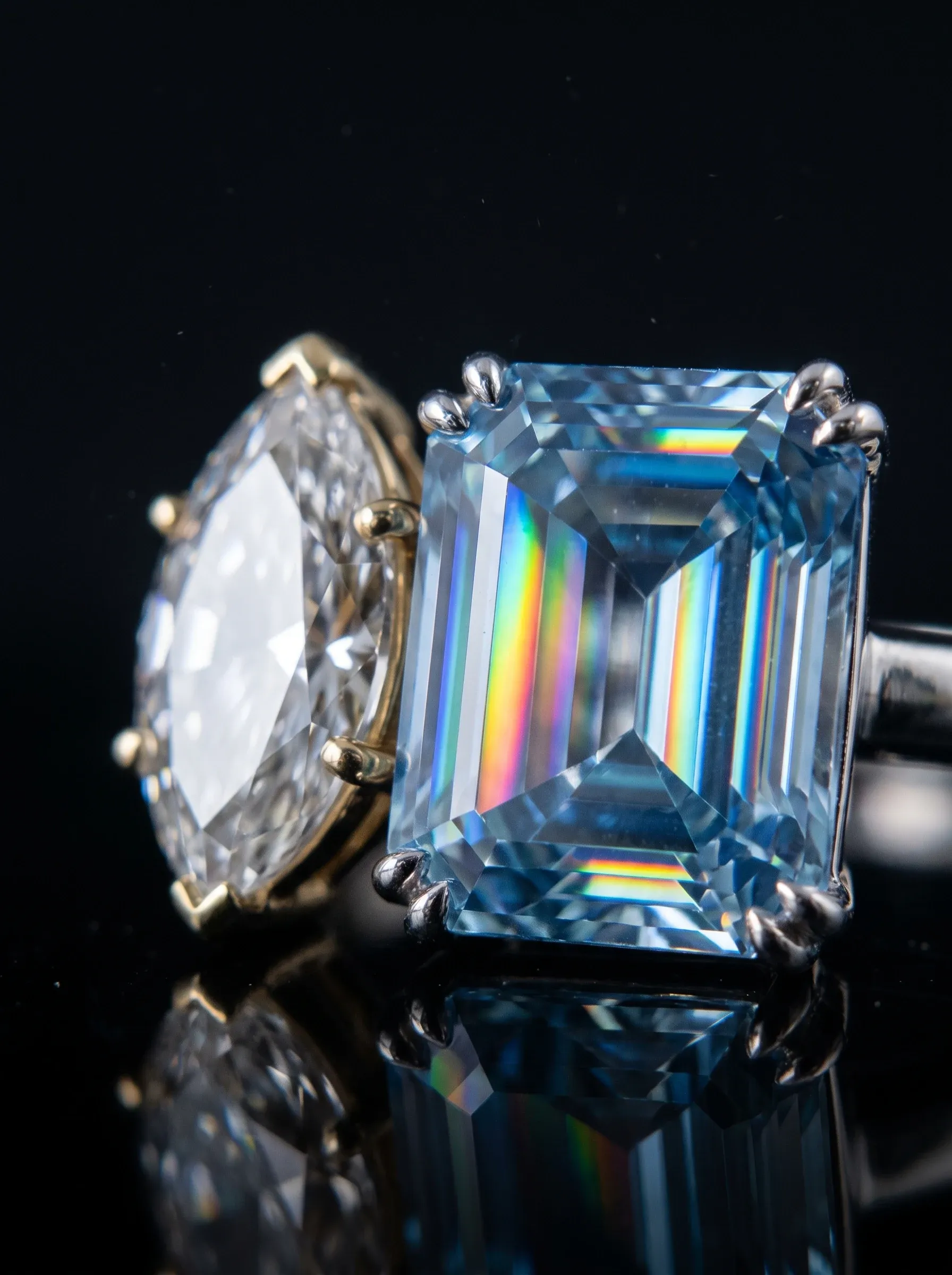 Emerald-cut moissanite throwing rainbow bands of fire next to a marquise diamond returning white light