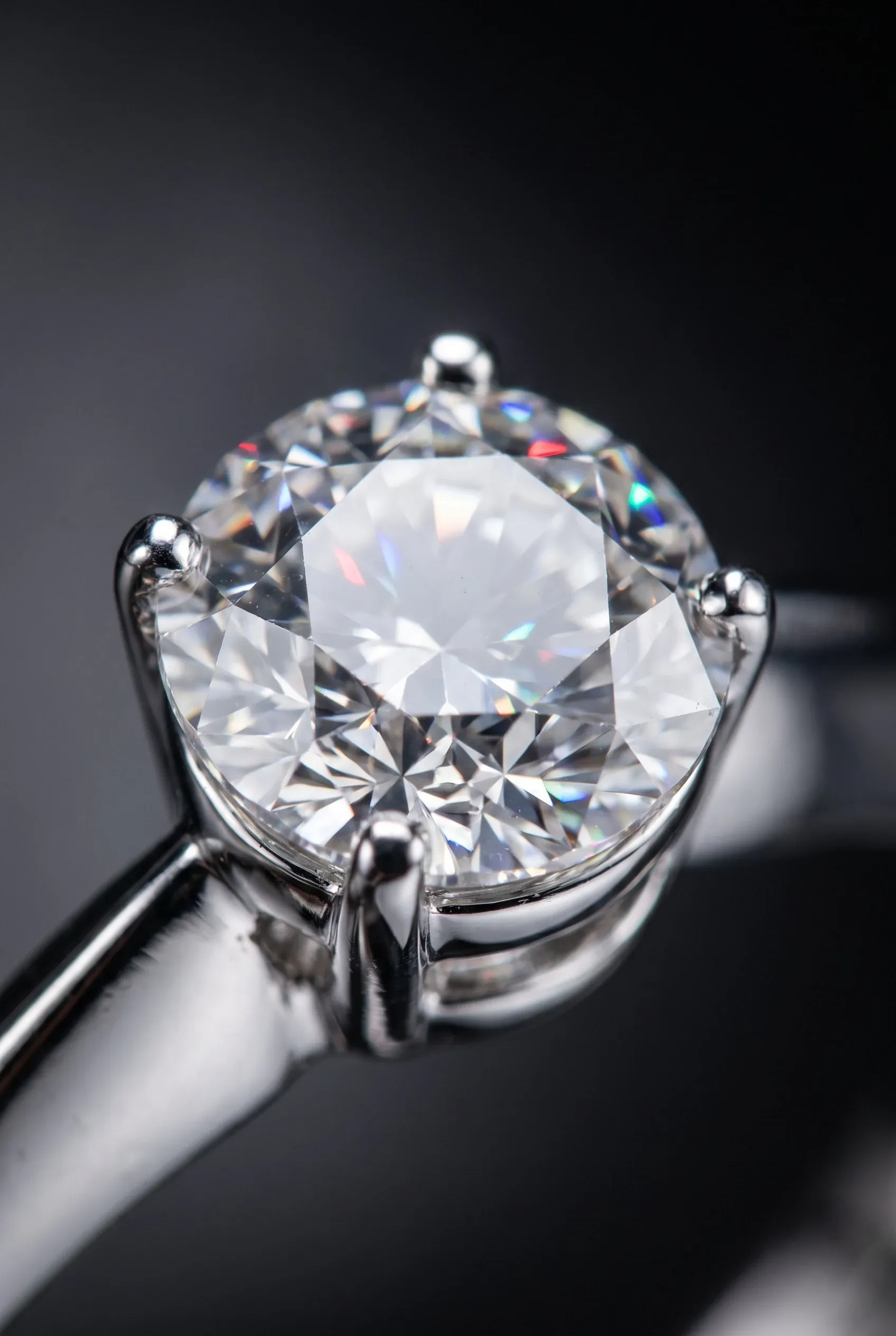 Macro of a round stone in a polished four-prong setting with small rainbow flashes inside the facets