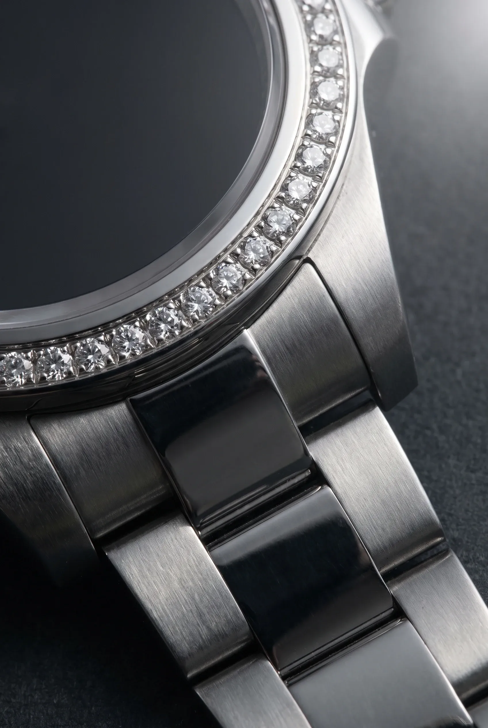 Macro of clear stones held by prongs and beads on a watch bezel and bracelet link.
